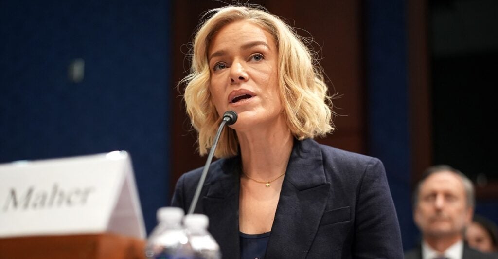 Katherine Maher sits in front of a microphone and answers questions as she looks at the politicians.