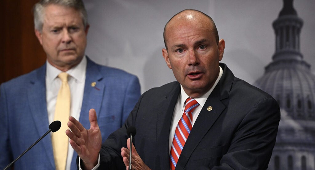 Mike Lee in a black suit with a striped tie
