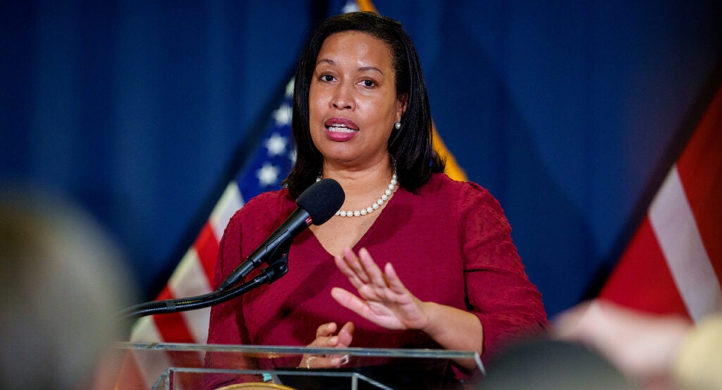 Muriel Bowser in a red blouse in front of American flags