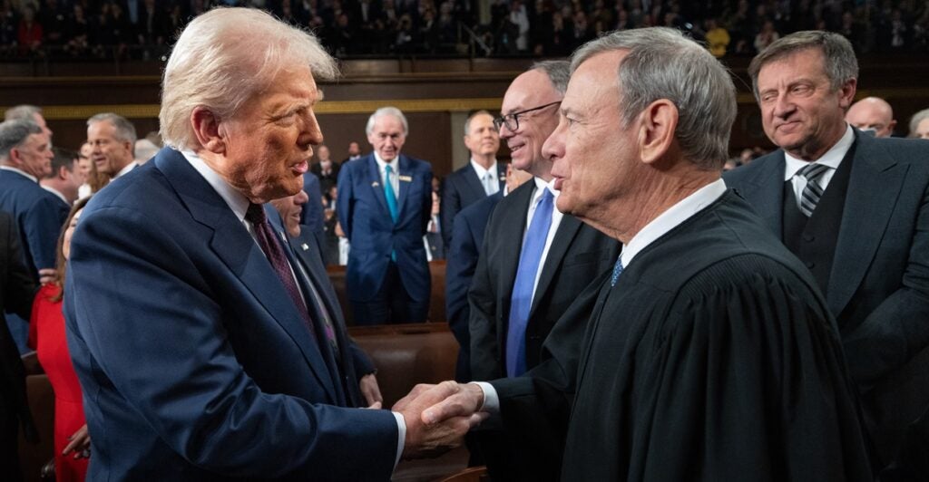 Donald Trump and John G. Roberts, Jr. shake hands while standing next to each other.