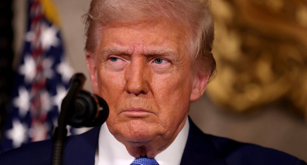 President Donald Trump gazes into the camera in a suit