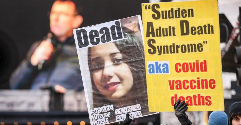 protesters holding up signs protesting COVID vaccination deaths