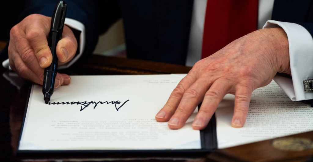 Close-up of President Trump's hands as he signs an executive order.