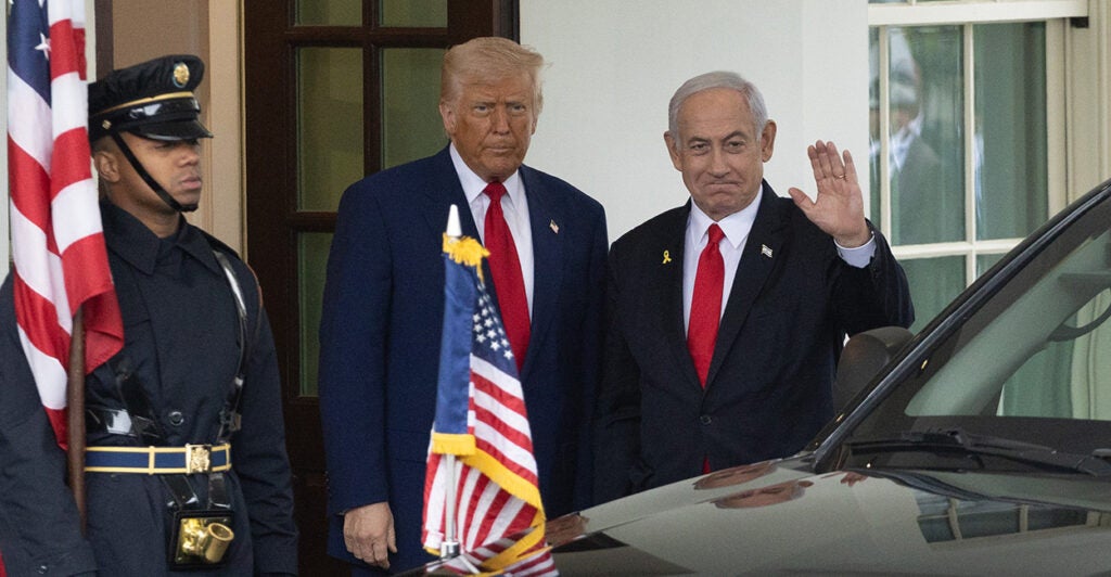 President Donald Trump and Israeli Prime Minister Benjamin Netanyahu stand side by side outside the White House. Both men are wearing dark suits and red ties.
