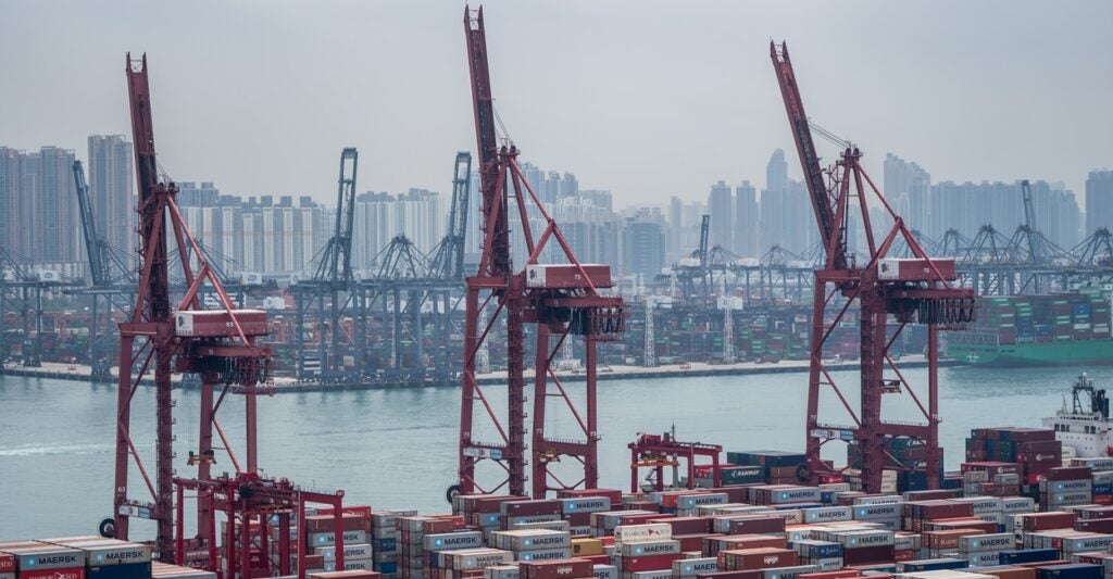 Shipping containers sit on the docks near cranes in Hong Kong.