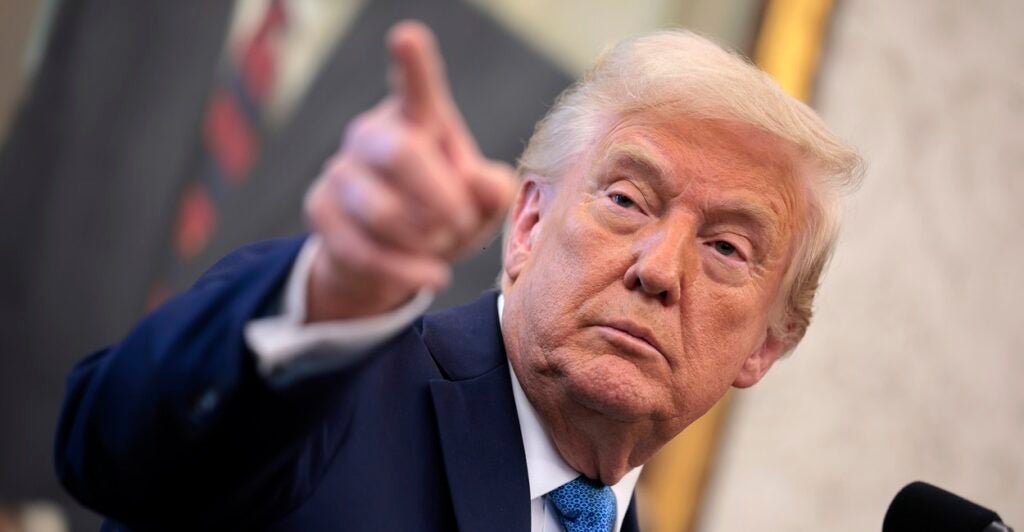 Donald Trump stands and uses his right hand to point to someone in a crowd.