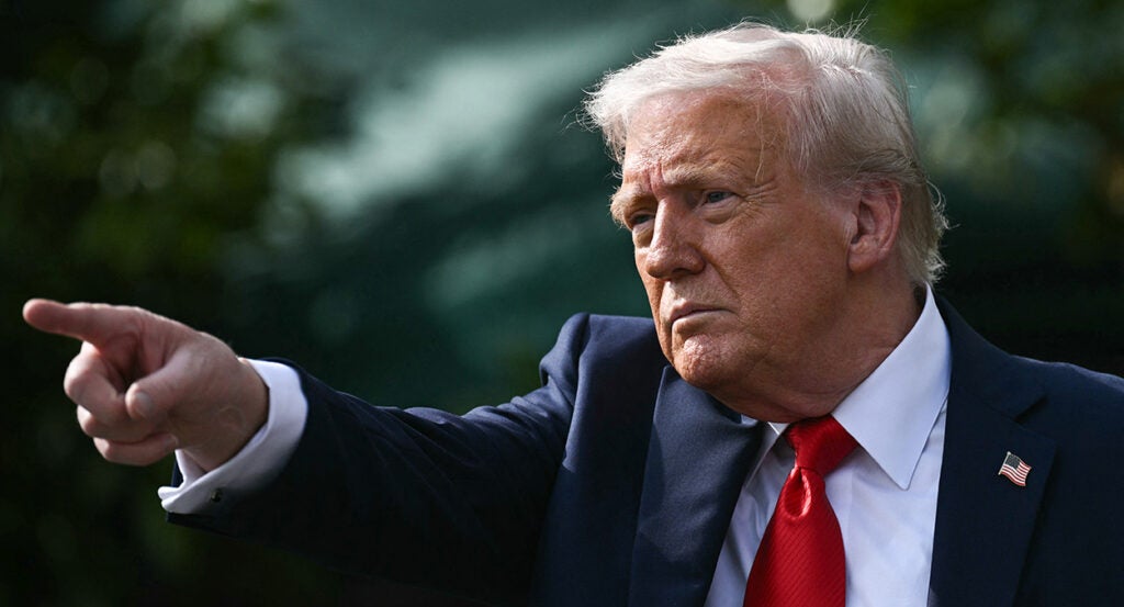 Donald Trump in a suit points off camera