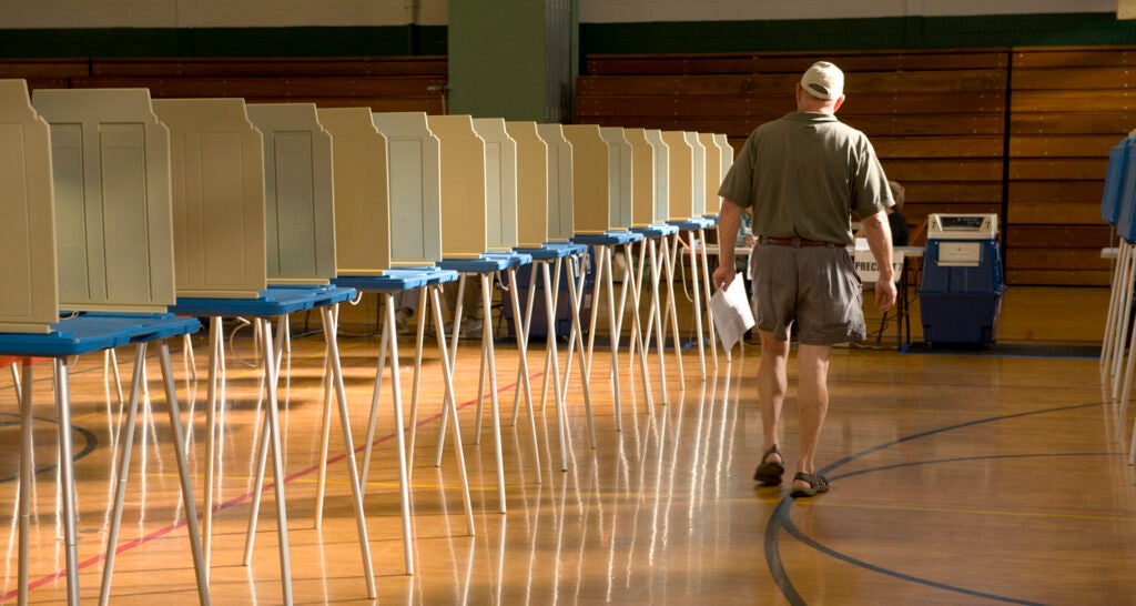 Solitary man walks past empty voting booths on way to cast his ballot.
