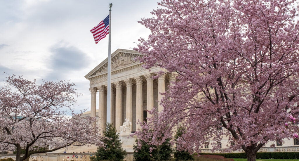The U.S. Supreme Court Building framed by blossoming cherry blossom trees.