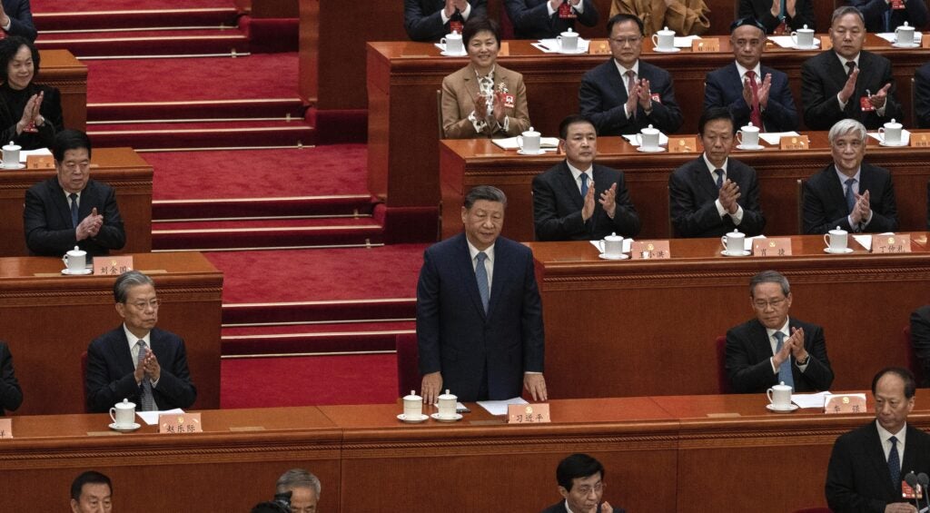 Chinese President Xi Jinping stands amid other Chinese Communist Party members, who applaud with assorted degrees of enthusiam.