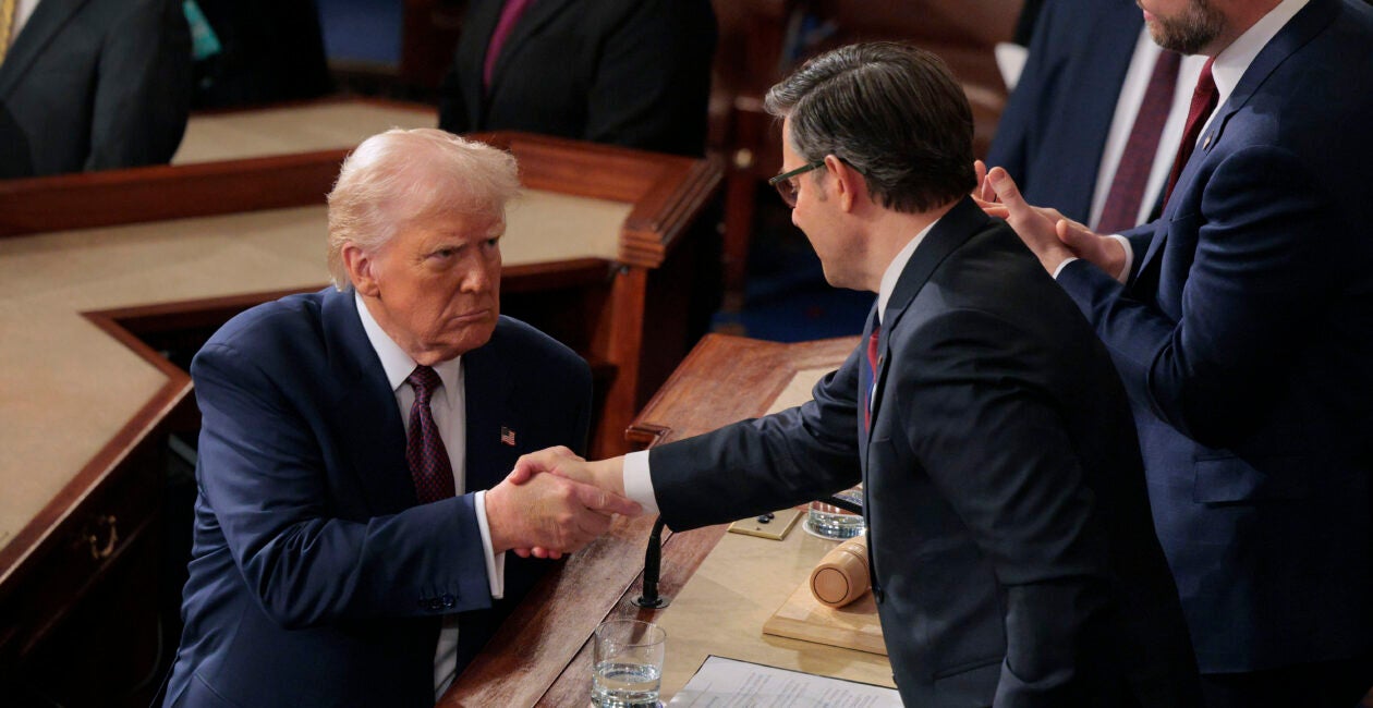Donald Trump, in a darl blue suit, shakes hands with Mike Johnson, dressed in a dark grey suit.