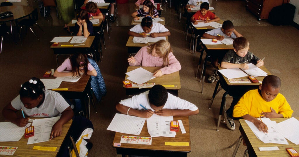 Young students about 10-12 years old sit intently at their desks taking a standardized test.