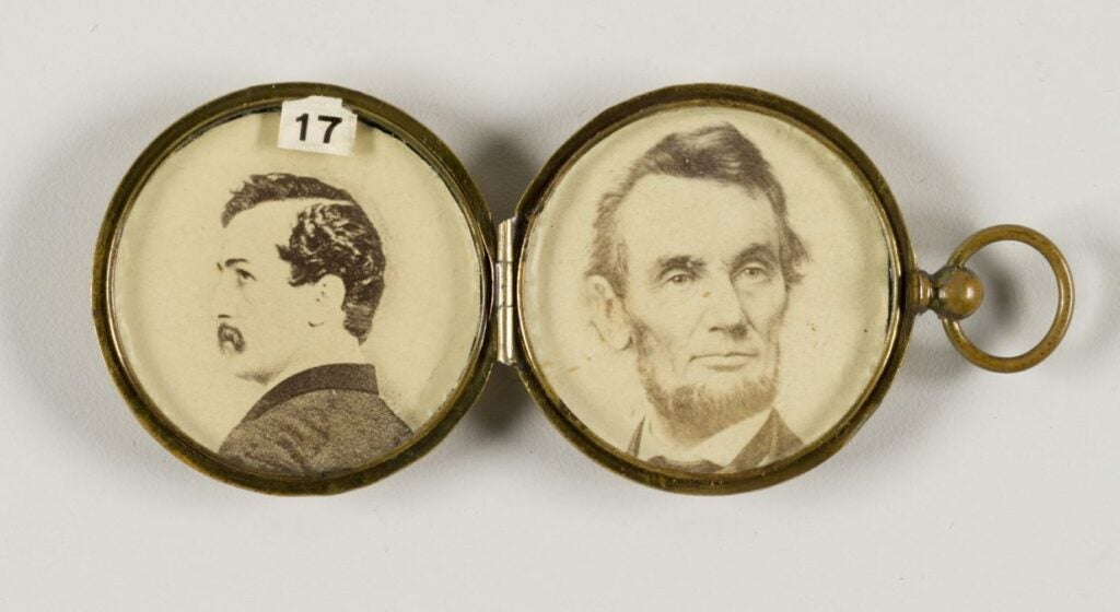 An antique gold locket contains a photo of President Abraham Lincoln and a photo of John Wilkes Booth.