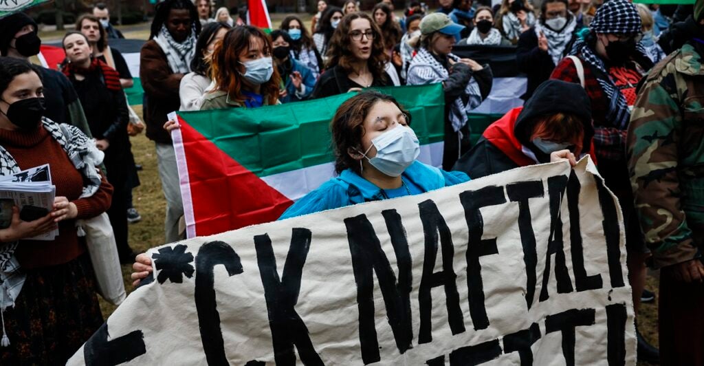 A college-aged woman holds up a sign with a profanity in it to protest a Jewish visitor to the campus of Harvard University.