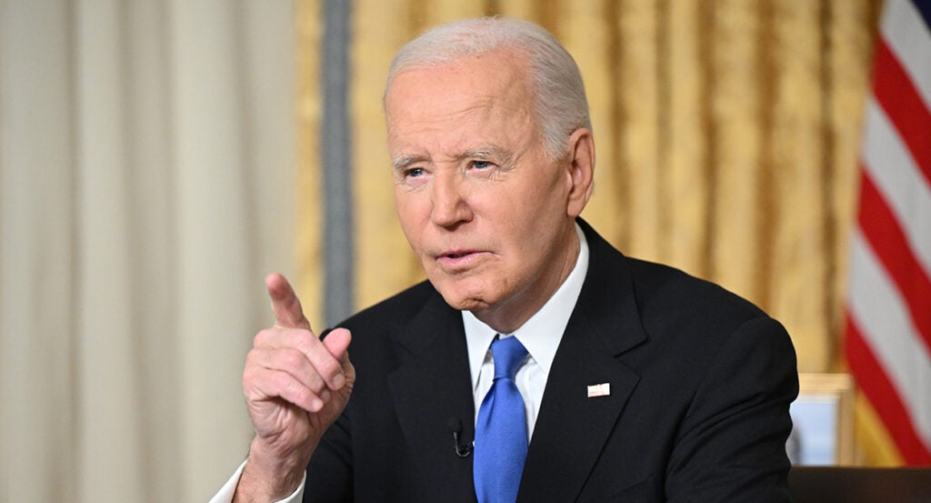 Joe Biden in a black suit points at the camera