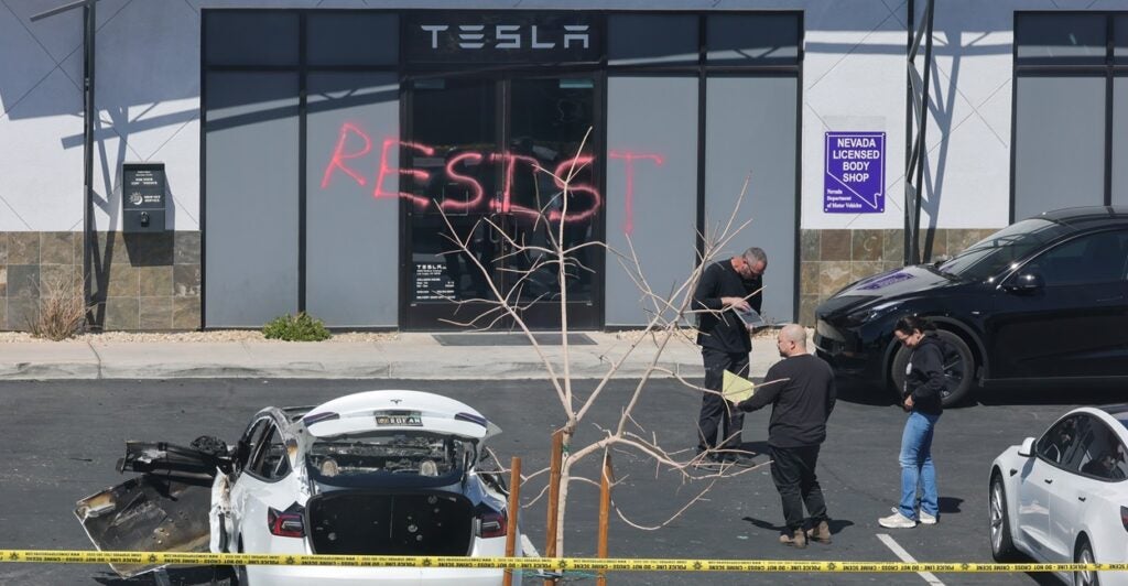 Investigators are at the parking lot of a Tesla store that was vandalized as the word "resist" is written in red spray paint on the building.