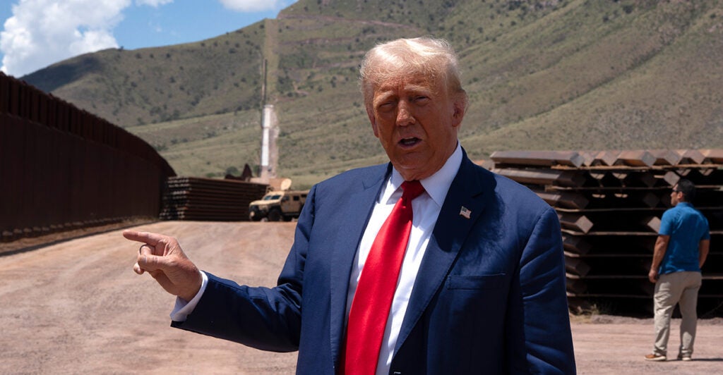 President Donald Trump delivers remarks at the U.S-Mexico border, gesturing with his right hand.