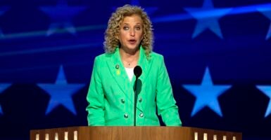 Debbie Wasserman Schultz stands at a podium in front of a microphone as she speaks at a conference.