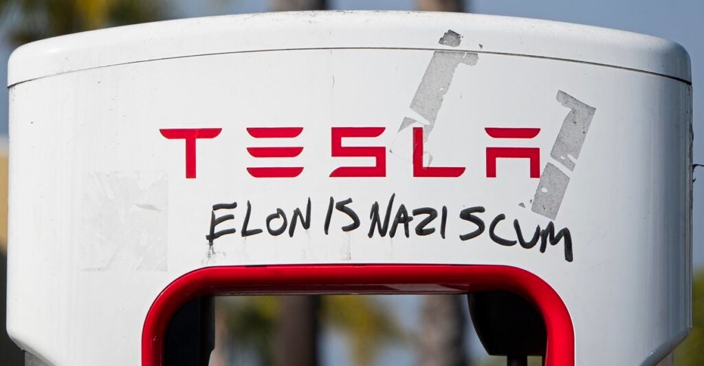A super charger station is vandalized with black letters calling Elon Musk a Nazi.