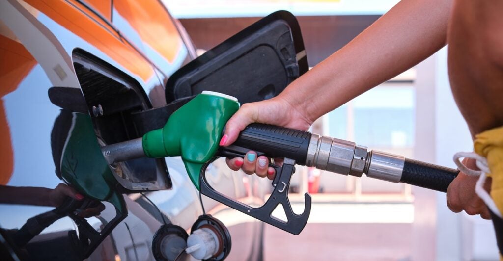 A person holds a gas pump while filling up a car with gas.