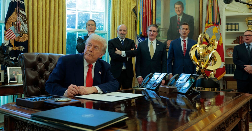 With Cabinet officials watching on, President Donald Trump signs an executive order in the Oval Office eliminating the regulations on shower heads.