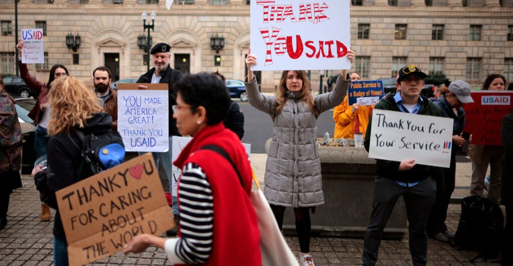 Supporters hold signs as former USAID employees are terminated after the Trump administration dismantled the agency.