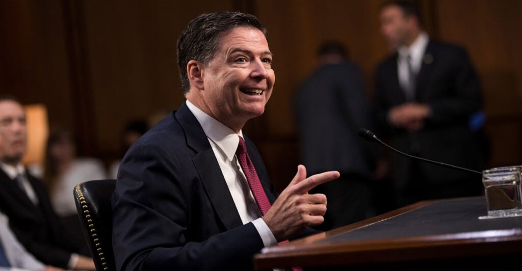 Former FBI Director James Comey points his finger like a gun during a Senate Intelligence Commitee hearing in 2017.