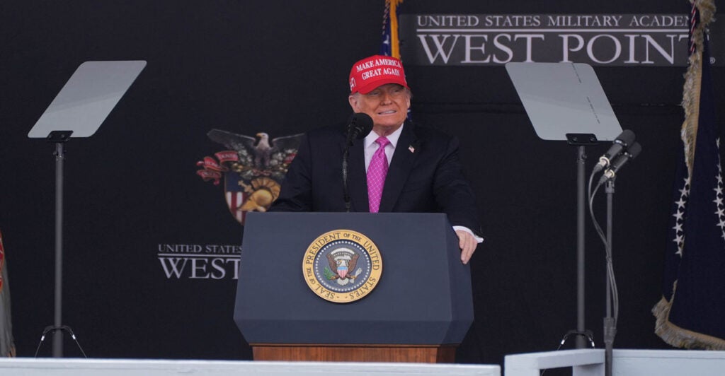 President Donald Trump in a Make America Great Again cap addresses graduates at West Point.