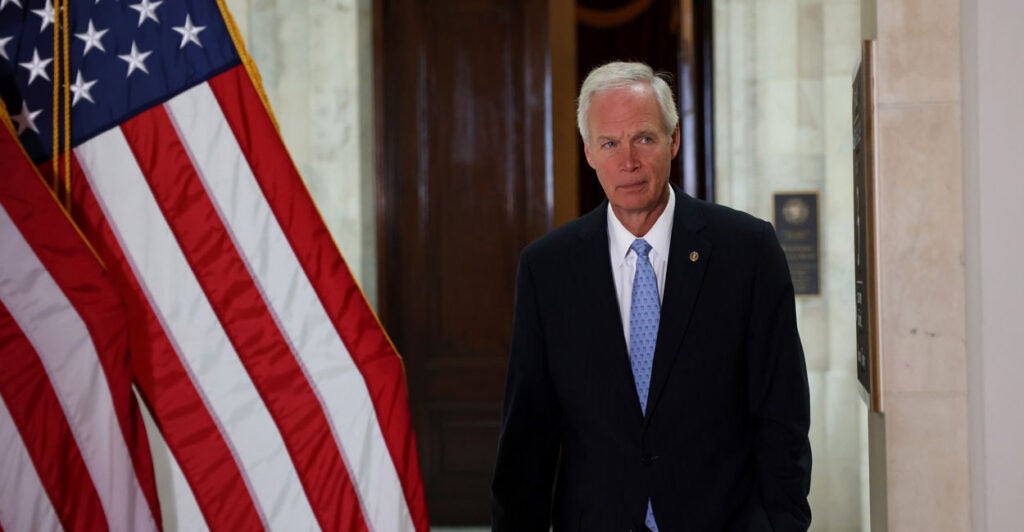 Sen. Ron Johnson strolls through the U.S. Capitol past an American flag.