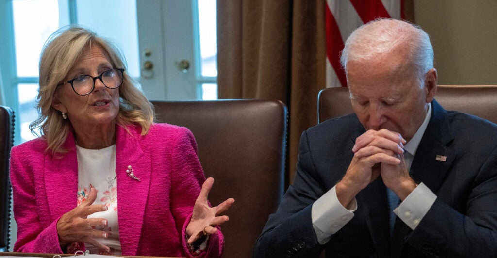 Jill Biden in pink jacket speaks at meeting of cabinet members, while President Joe Biden, hands clasped, "rests his eyes."