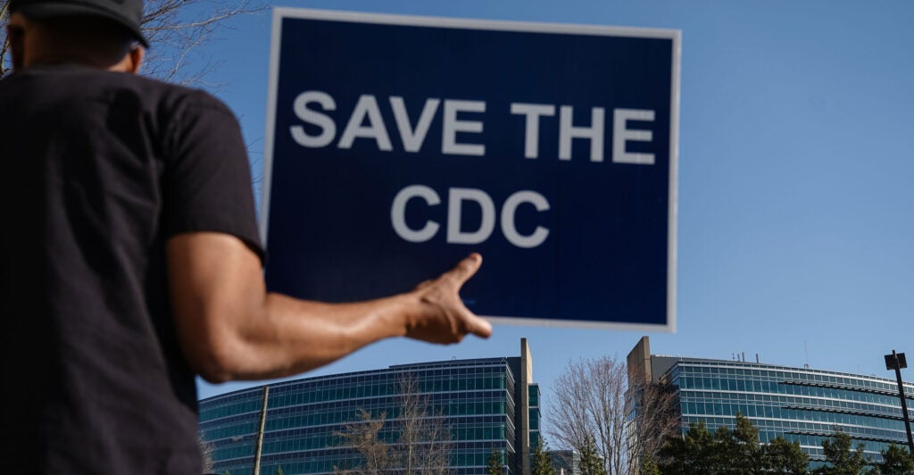 People protesting personnel cuts at the Centers for Disease Control hold signs outside the organization's Atlanta, Georgia, headquarters on March 12.