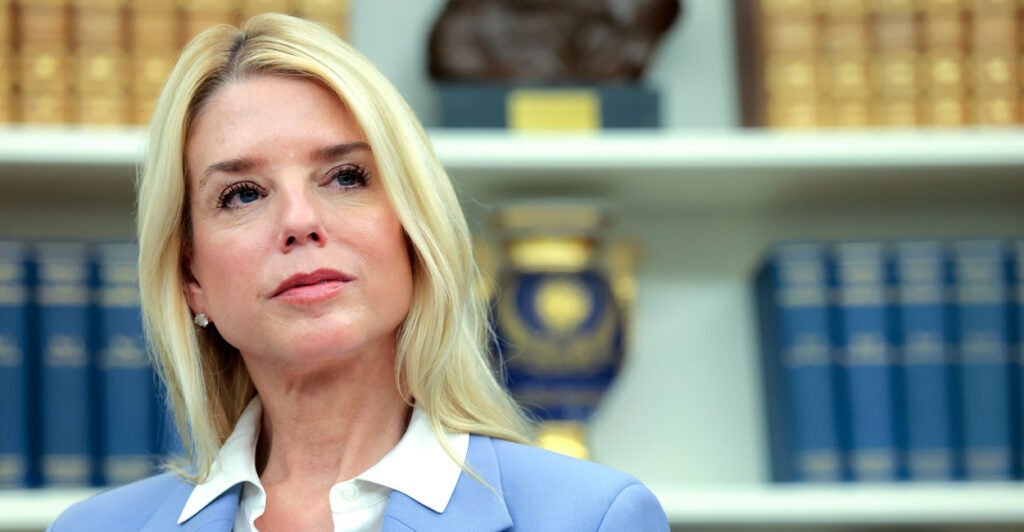 Attorney General Pam Bondi, with a backdrop of bookshelves with law books.