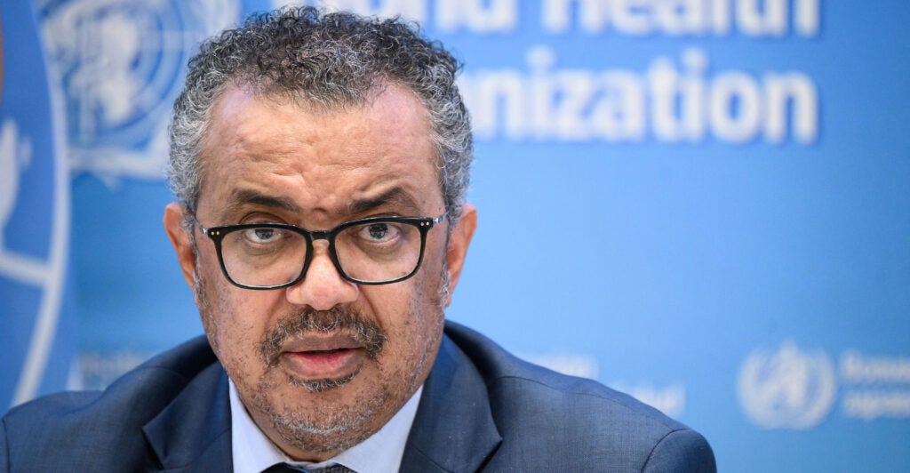World Health Organization Director-General Tedros Adhanom Ghebreyesus, with the WHO name and logo on the wall behind him