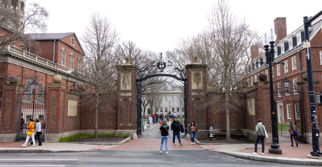 A long shot of two students entering the main gain into the campus of Harvard.