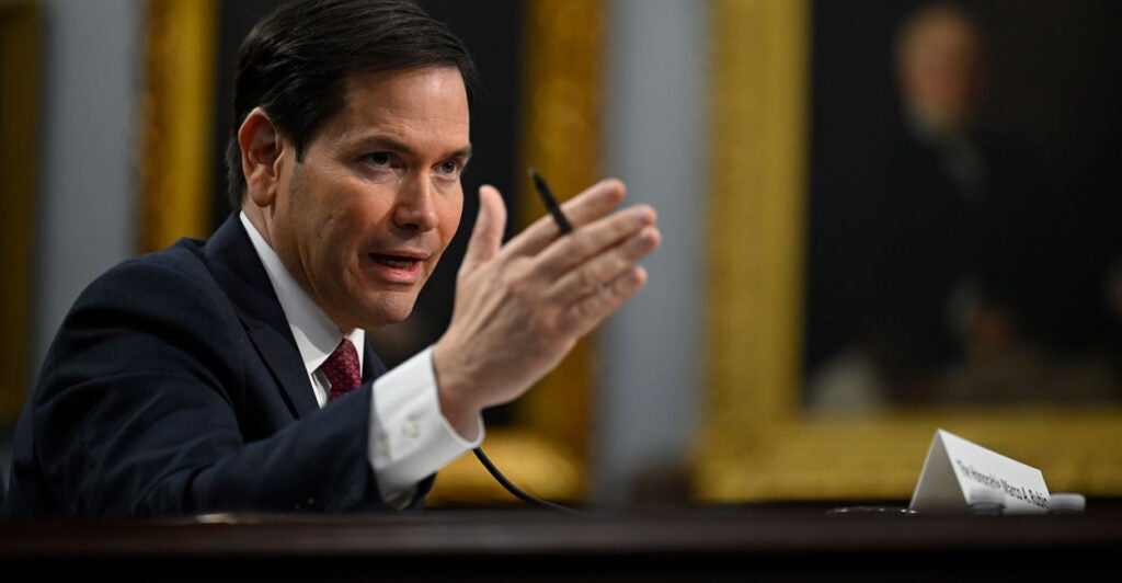 Secretary of State Marco Rubio testifies before members of Congress in a dark suit and tie.