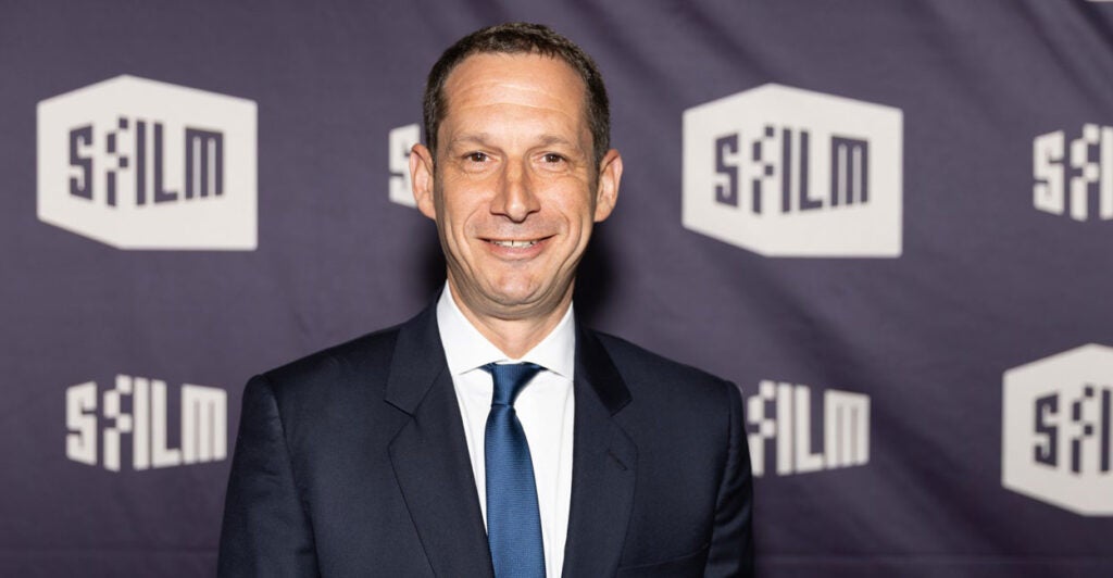Daniel Lurie looks straight ahead and smiles as he poses for a photo at a film festival.