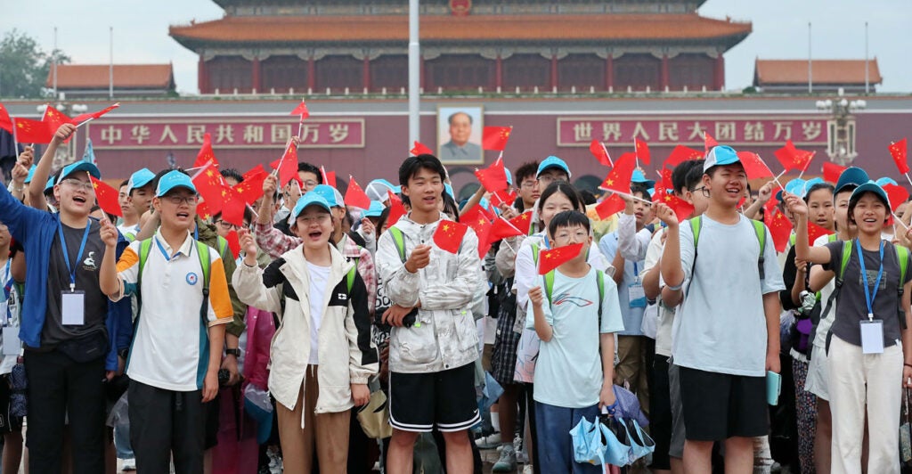 A group of young Chinese waving red flags in Tiananmen Square.