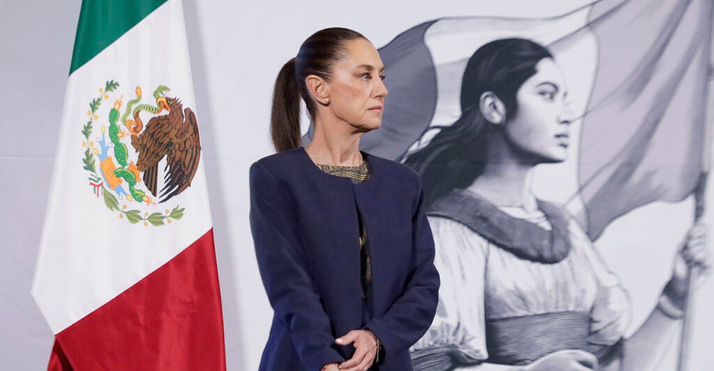 Claudia Sheinbaum in front of a Mexican flag