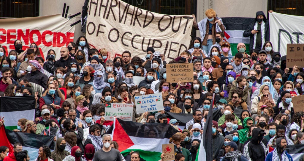 A large crowd of anti-Israel protesters gather at Harvard Yard, waving Palestinian flags and signs reading "Genocide in Gaza."
