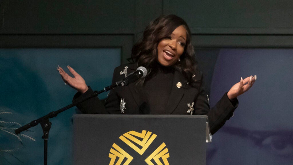 Jasmine Crockett behind a podium, arms spread wide.