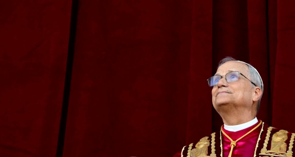 American-born Pope Leo XIV gazes toward heaven against a burgundy background.