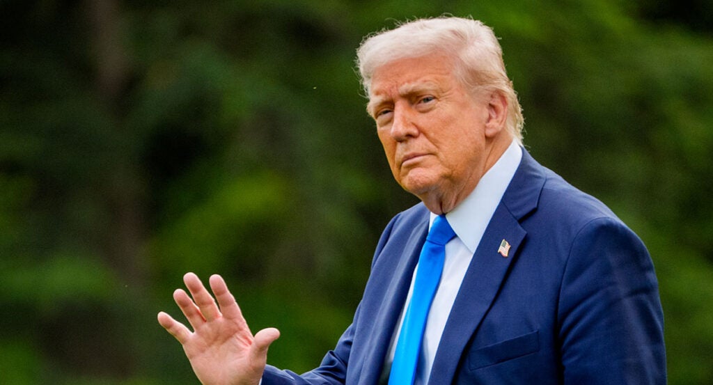 Donald Trump waves in a blue suit with a blue tie
