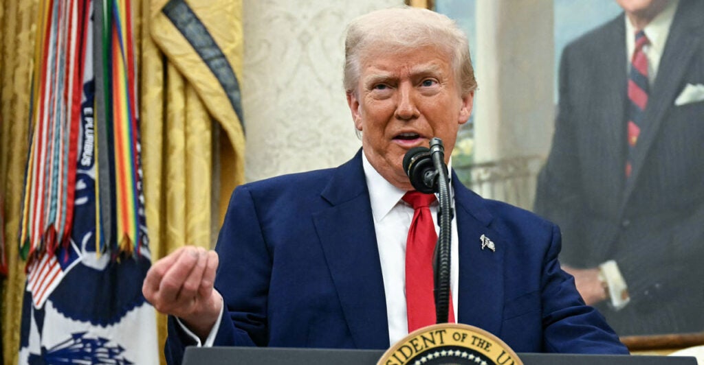 President Trump gestures while speaking behind a podium.