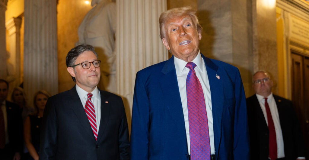 With Speaker of the House Mike Johnson, R-La., looking on, President Donald Trump speaks to reporters Tuesday at the Capitol after a House Republican Conference meeting.