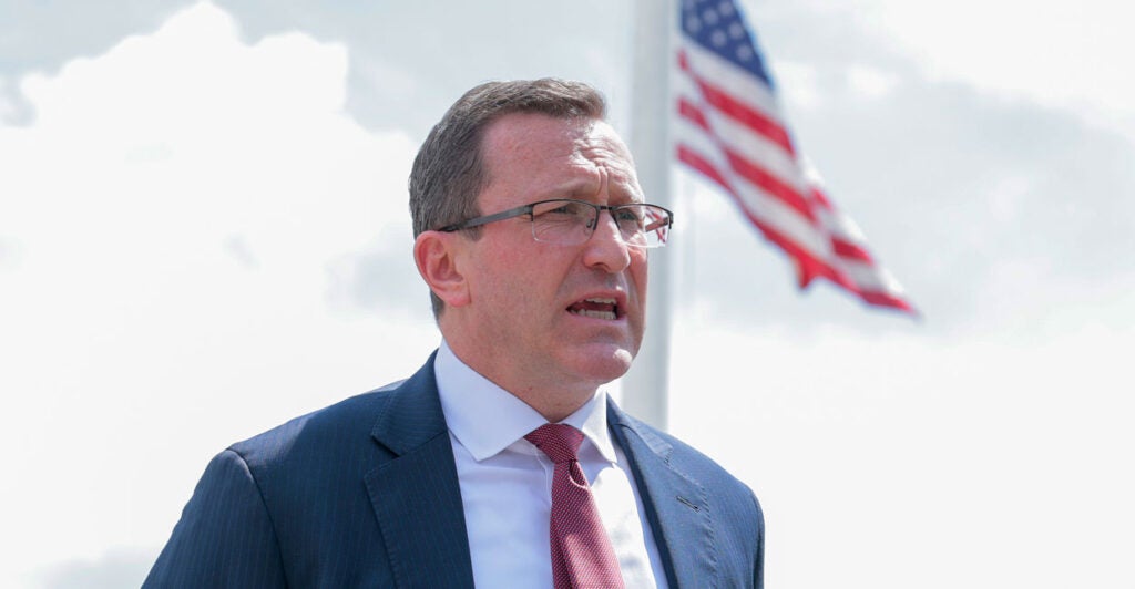 Religious liberty lawyer Eric Baxter with a flag unfurled on a flagpole behind him