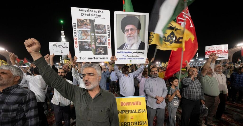 Iranian protesters shout anti-U.S. slogans while carrying a sign that says, "America is the great Satan."