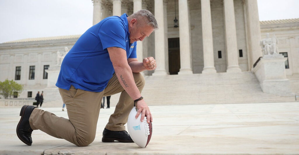 Former high school football coach Joe Kennedy takes a knee in front of the U.S. Supreme Court