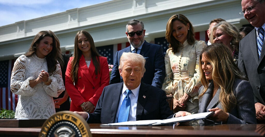 First lady Melania Trump (seated, right), Sen. Ted Cruz (standing, center), and others look on after President Donald Trump signed the Take It Down Act on Monday.