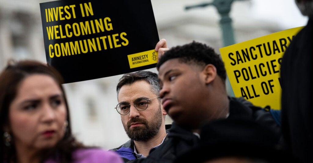 People hold signs saying “Invest in Welcoming Communities” during a press conference with congressional Democrats in support of sanctuary city mayors outside the U.S. Capitol.