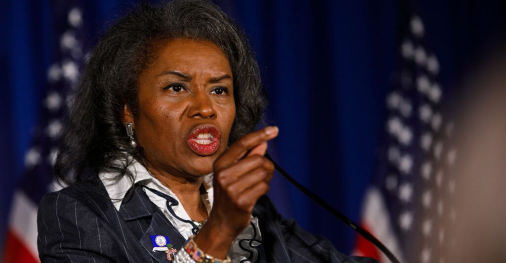 Virginia Lt. Gov. Winsome Earle-Sears speaks at a podium with American flags in the background and gestures by pointing her finger to the audience